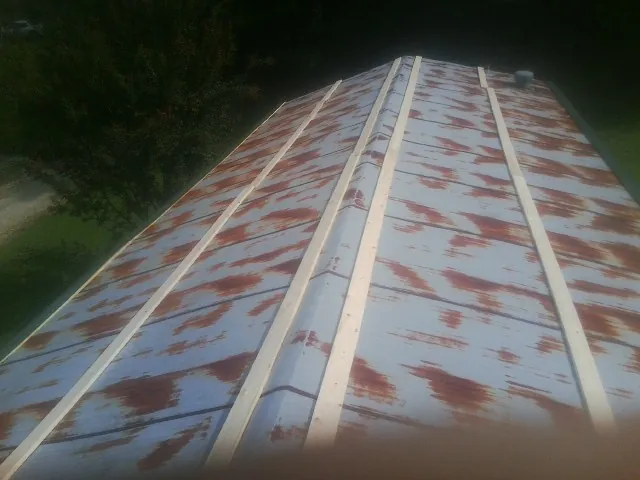Rusted metal roof panels with new wood purlins before replacement — Storm Damage Roof Repair in Champion by Roofing Brothers