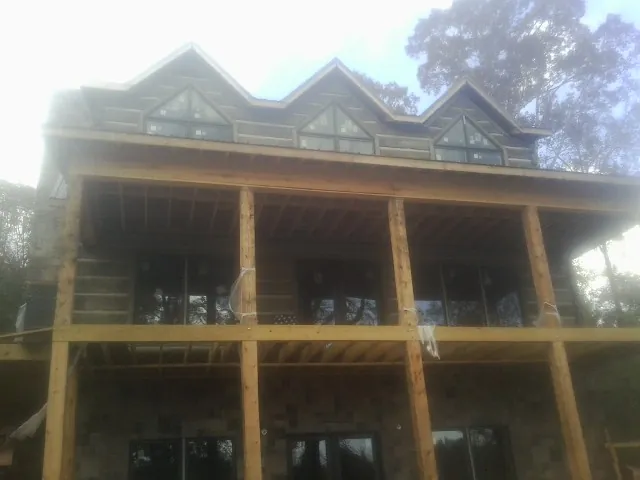 Dormers and porch framing on a large log home under construction — Roof Coating work by our crew in Champion