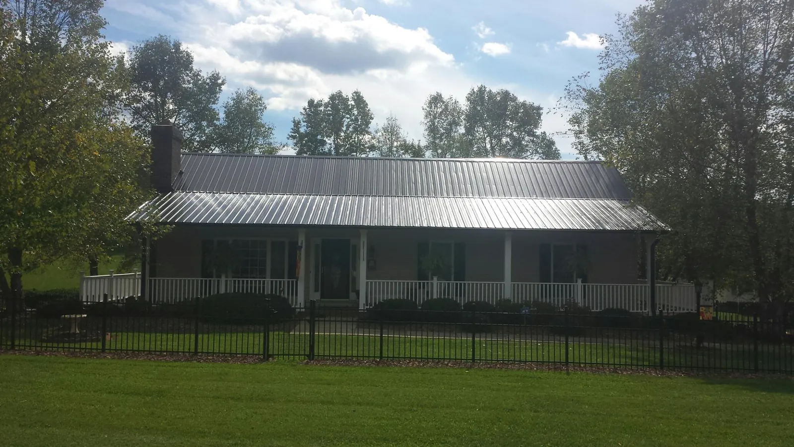 Gray metal roof on a brick ranch with a full width front porch — Gutter Guard Installation work by our crew in Champion